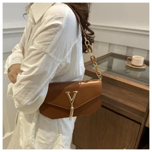 Brown shoulder bag detail view, featuring metallic V logo and stylish tassel charm.