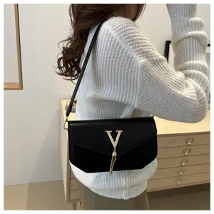 Detailed view of the stylish black shoulder bag with metal V logo and elegant tassel pendant.