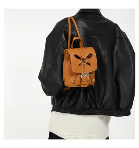 Gros plan détaillé du mini sac à dos en cuir marron avec un joli rabat ajouré papillon.