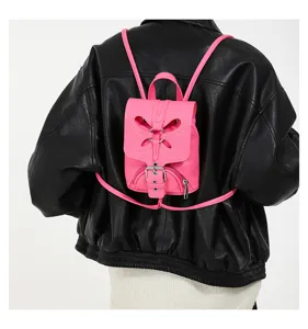Vue détaillée du mini sac à dos rose avec rabat papillon unique et boucle en métal chic.
