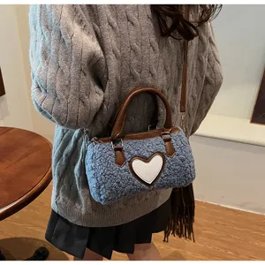 Détail de sac Boston duveteux bleu confortable, sac bandoulière peluche avec patch cœur blanc.