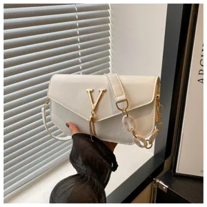 White leather shoulder bag detail showing metal V logo, tassel and chain strap design.
