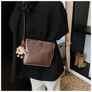 Sac bandoulière en cuir marron avec charm peluche mouton duveteux mignon, style tendance.