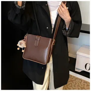Vue de détail rapprochée du sac seau élégant en cuir marron avec charmant pendentif peluche.