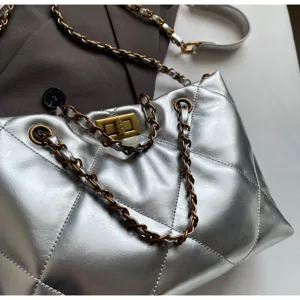 Silberne gesteppte Umhängetasche mit Kette und Drehverschluss für modebewusste Damen.