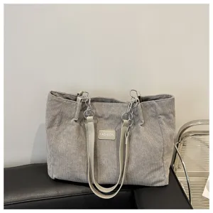 Graue Cord-Schultertasche Detailansicht mit Metallkettenriemen und feinem Stoff.
