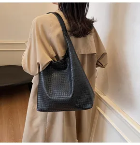 Vue détaillée d'un sac porté épaule tressé noir, accessoire vintage élégant et pratique.