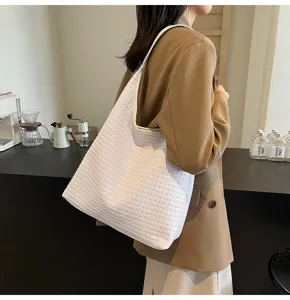 Gros plan détaillé d'un élégant sac cabas tressé blanc porté par un mannequin au café.