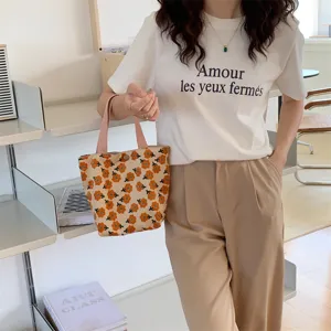 Cute daisy print corduroy lunch tote bag with casual white t-shirt and trousers set.