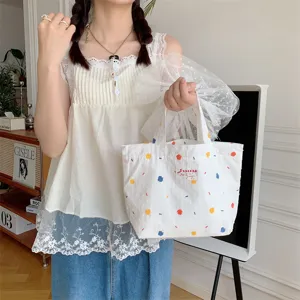 Vista dettagliata della borsa in tela bianca con pois colorati, accessorio quotidiano casual.