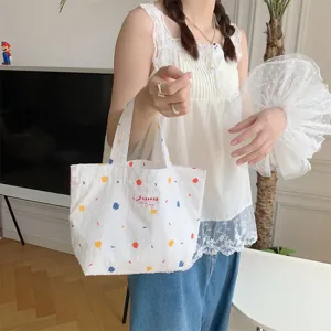 Vista dettagliata della borsa tote in tela bianca con pois colorati e design compatto.