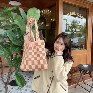Detailed view of the stylish pink and brown checkered knitted tote bag in a cafe setting.