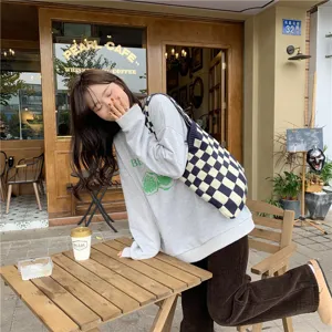 Stylish knitted checkered tote bag detail in street cafe scene, casual autumn fashion look.