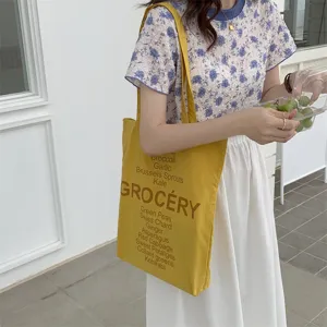 Detail view of yellow canvas tote bag with vegetable graphic print for everyday casual wear.
