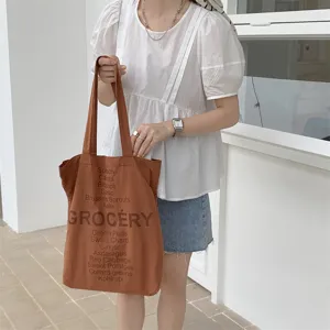 Brown canvas tote bag detail featuring vintage grocery and vegetable letter print design.