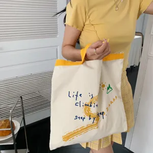 Canvas tote bag detail view, casual shoulder bag with inspiring text print and graphic.