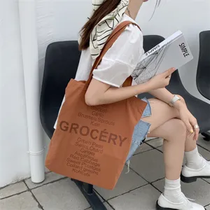 Detail view of the brown canvas tote bag featuring grocery letter print and vegetable words for daily.