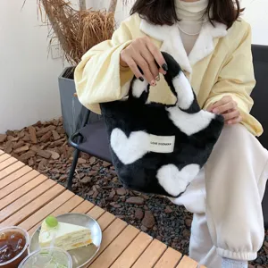 Detailaufnahme der schwarz-weißen Plüsch-Herztasche, weiche Felltextur und süßer Stil.
