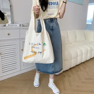 Detailed close-up view of large canvas shoulder bag with quote print in cozy room.