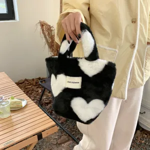 Nahaufnahme der schwarz-weißen Plüsch-Handtasche mit Herzmuster, weicher Textur und tollem Stil.