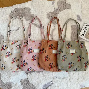 Detailed view of large corduroy tote bag showing colorful letter prints and shoulder straps.
