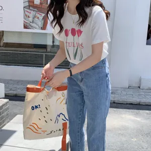 Détail de sac cabas en toile avec sangles contrastées et imprimés ludiques pour un usage quotidien.