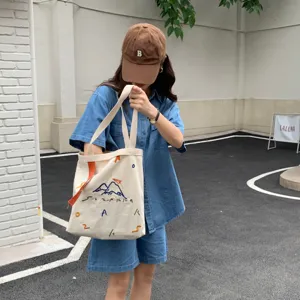 Vue détaillée du sac cabas en toile décontracté avec broderie créative et sangle.