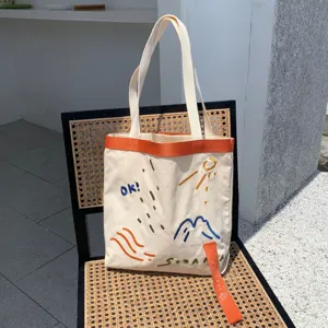 Sac cabas en toile avec motifs brodés et sangle contrastée pour un usage quotidien.