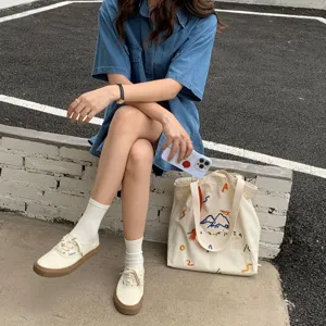 Vue détaillée d'un cabas en toile beige avec broderie colorée, style urbain.