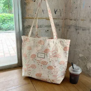 Detailaufnahme der vintage rosa floralen Jacquard Tragetasche mit goldenen Details am Tisch.