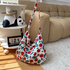 Canvas shoulder bag detail showing red rose print pattern and long strap in cozy room setup.