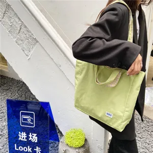 Light green canvas tote bag featuring stylish plaid lining, perfect for daily casual wear.