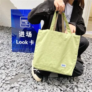 Detail view of light green canvas tote bag with stylish plaid straps, casual student shoulder bag.