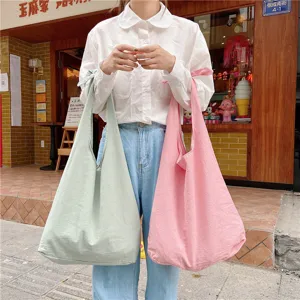 Canvas tote shoulder bag detail view, casual solid color sling bag in pink and green hues.