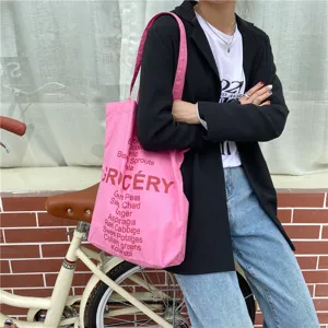 Detailed view of pink canvas grocery tote bag with stylish English typography print.