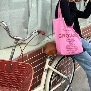 Detail shot of pink canvas tote bag with grocery vegetable print for daily casual street wear.