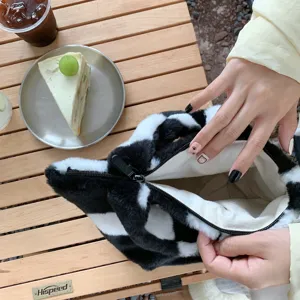 Detaillierte Ansicht der schwarz-weißen Plüschtasche mit weichem Stoff und praktischem Reißverschluss.