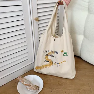Beige canvas tote bag with artistic letter print and mountain graphic for daily use