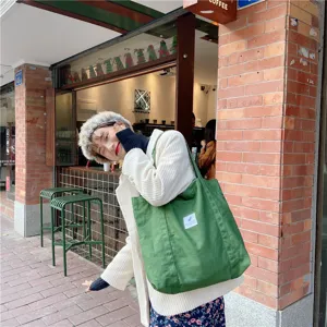 Vue détaillée d'un sac cabas en toile verte porté par un modèle dans un style rétro.