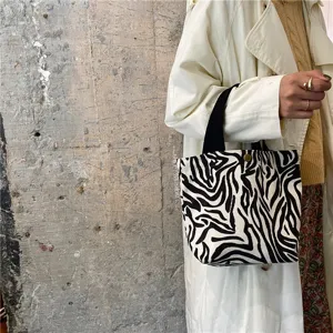 Zebra pattern mini tote bag detail, featuring black handles and snap button closure close-up.
