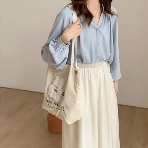 Close-up detail of the cute white rabbit embroidery corduroy shoulder tote bag in daily wear.