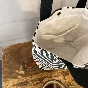 Detail view of the black and white striped canvas tote bag with inner pocket and black handles.