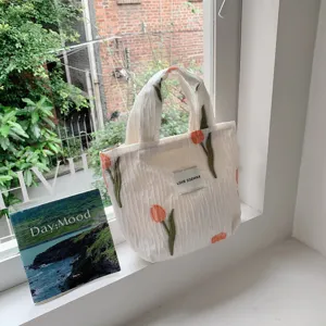 Tulip embroidered white pleated tote bag detail view, casual window sill scene display.