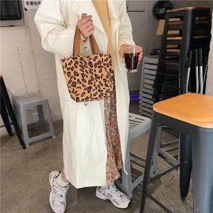 Closeup detail of the trendy leopard print corduroy tote bag with brown handles in use.