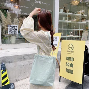 Outdoor scene detail shot of a light green cotton linen shoulder tote bag, casual lifestyle.