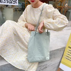 Detail view of a casual light green cotton linen tote bag with thin straps for daily wear.