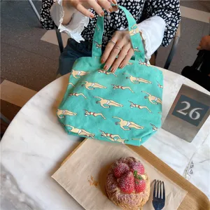 Green canvas bento bag with cute swimmer print, compact handbag for lunch box and daily use detail.