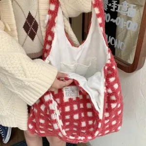 Detail view of red white plaid plush tote bag interior pocket and soft fabric label.