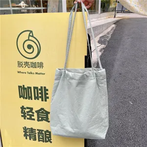 Detail view of light green casual canvas tote bag with slim shoulder straps and soft texture.