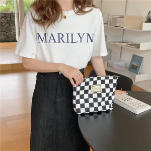 Pochette de maquillage en toile à carreaux noirs et blancs, détail de sac élégant.